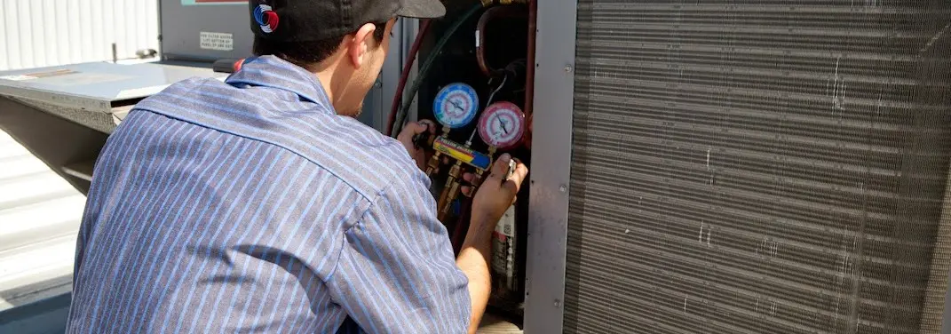 HVAC technician servicing a condenser unit in Medical Lake